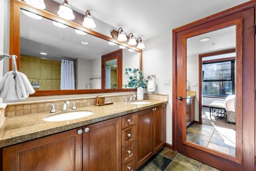 a bathroom with two sinks and a large mirror at Pool, Hot Tub & Golf: Everline Resort Corner Suite in Olympic Valley