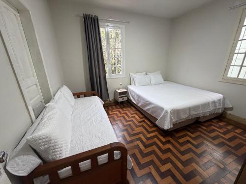 a bedroom with two beds and two windows at Espaço do Imperador in Petrópolis