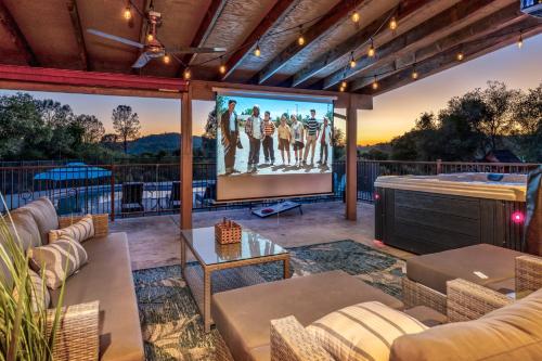 an outdoor patio with a large screen with a movie at Mountain Elegance w/ pool, spa, projector in Coarsegold