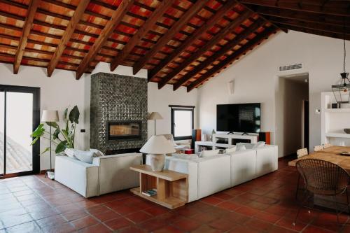 a living room with white couches and a fireplace at Beautiful villa with private pool and mountain views in Jimena de la Frontera