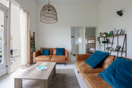 a living room with brown couches and blue pillows at Rekerlanden 275 in Warmenhuizen