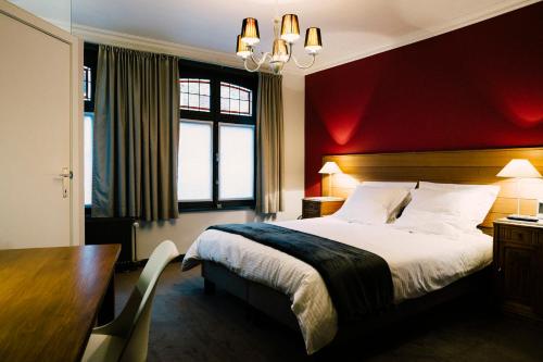 a bedroom with a bed with a red wall at Tripel B in Bruges
