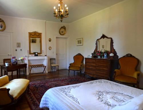 a bedroom with a bed and a mirror and chairs at Chambres d'Hôtes Launay Guibert in Miniac-Morvan
