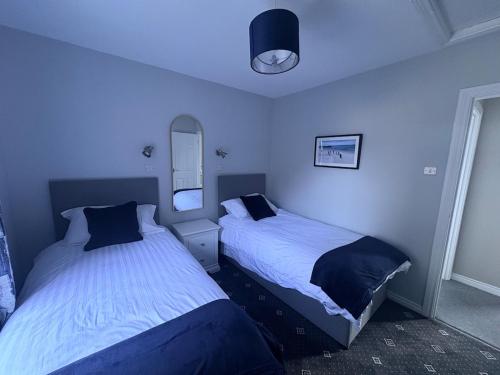 two beds in a bedroom with blue walls at Bide A While at the Port in Portrush