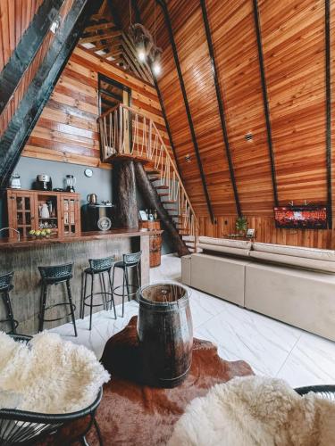 a living room with a wooden ceiling and a staircase at Chalé Rio Capetinga 01 in Anchieta