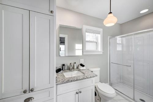 a white bathroom with a toilet and a shower at The Little Bungalow in Houston