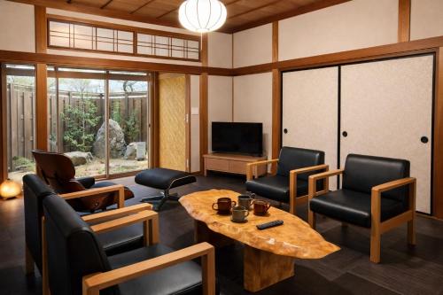 a living room with chairs and a table and a television at 加美屋リゾート出雲大社神迎の道 杵と月 in Taisha