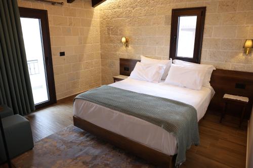 a bedroom with a large bed with two windows at Hotel Panorama in Berat