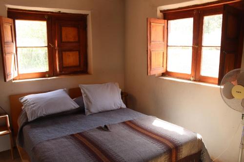 a bed in a bedroom with two windows at Casa Garces in San Pedro de Atacama
