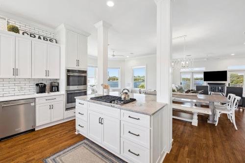 a kitchen with white cabinets and a dining room with a table at Dock N Dune by 30A Escapes in Seagrove Beach