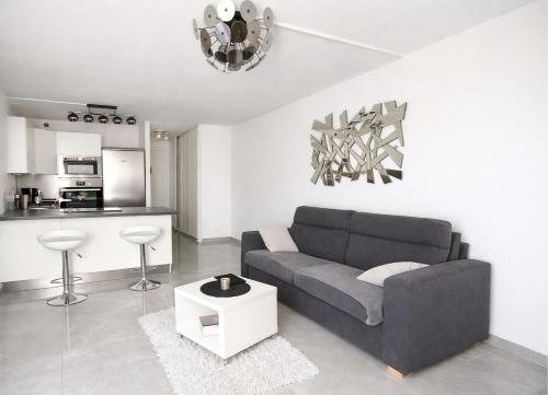 a living room with a gray couch and a kitchen at Studio cosy, Centre Port, Piscine, proche plage in Cap d'Agde