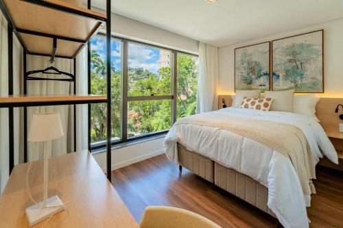 a bedroom with a bed and a large window at apartamento em Itaipava novo, Granja Brasil Resort in Petrópolis
