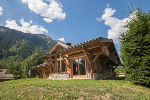 a wooden house on a hill with mountains in the background at Chalets Zaria Garden Fireplace near Ski Lift - Happy Rentals in Argentiere