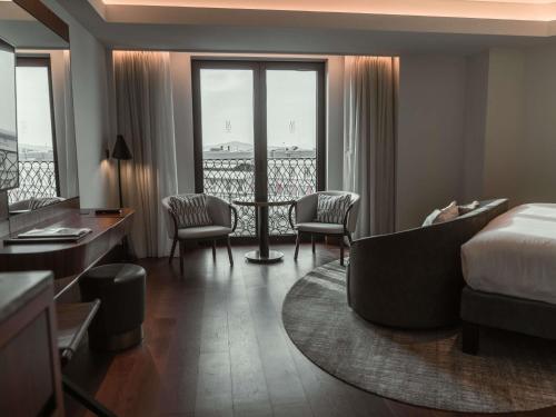 a hotel room with a bed and a desk and chairs at Athens Capital Center Hotel - MGallery Collection in Athens