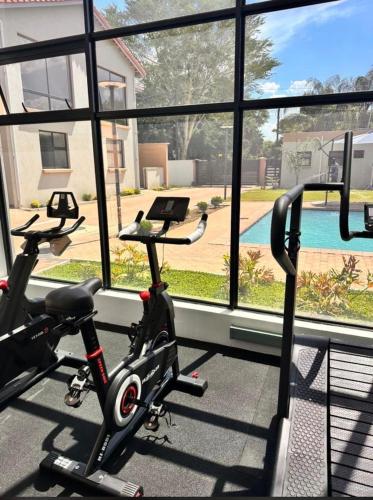 a gym with a treadmill and a bike in front of a window at Gate Beautiful in Gaborone