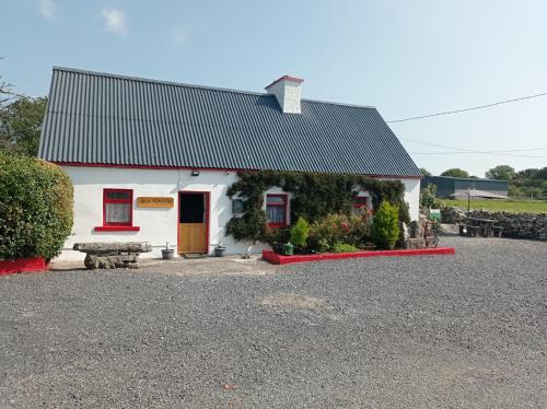 a small white house with a red door at Historic old Cottage Co Mayo in Ballinrobe