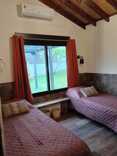 two beds in a room with a window at Pinot Noir in Piriápolis