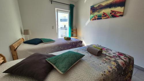 a bedroom with two beds and a window at Apartamentos Pátio da Aldeia in Armação de Pêra