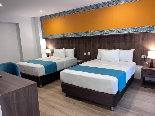 a hotel room with two beds and a desk at Hanaqua Cusco Hotel in Cusco