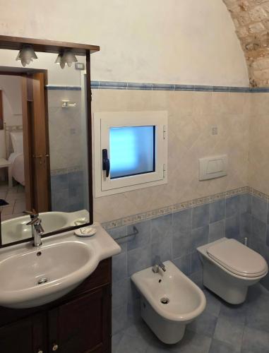 a bathroom with a sink and a toilet and a tv at Nonno Pasquale house in Locorotondo