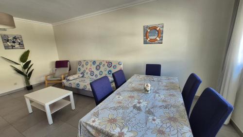 a dining room with a table and blue chairs at Apartamentos Pátio da Aldeia in Armação de Pêra