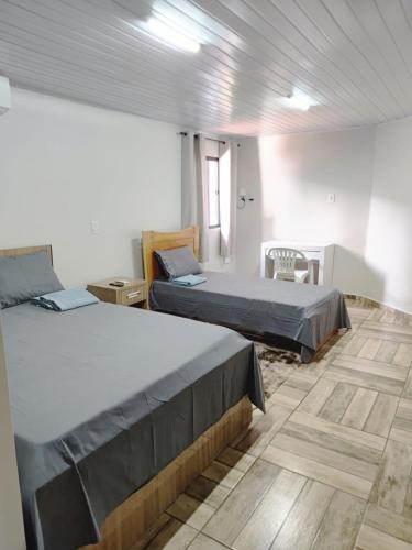a bedroom with two beds and a table and a chair at Espaço aconchegante ótima localização in Foz do Iguaçu