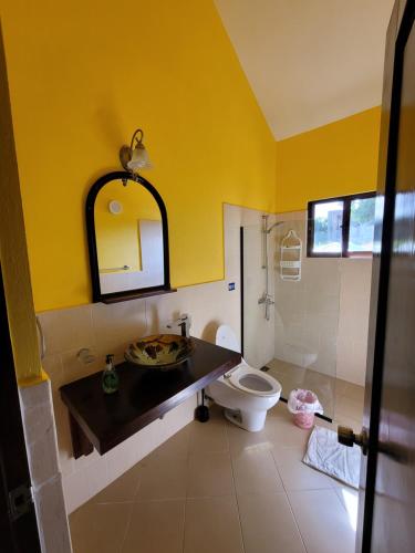 a yellow bathroom with a toilet and a sink at B&B Pavillion in Sosúa