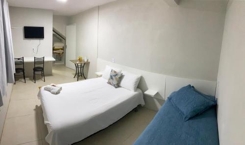 a bedroom with a white bed and a blue couch at Pousada le sorelle in Rosário do Sul