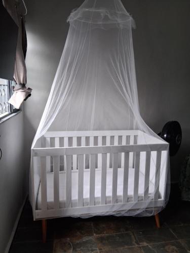 a white crib with a canopy in a room at Pousada Cantinho da Idná in Uberlândia