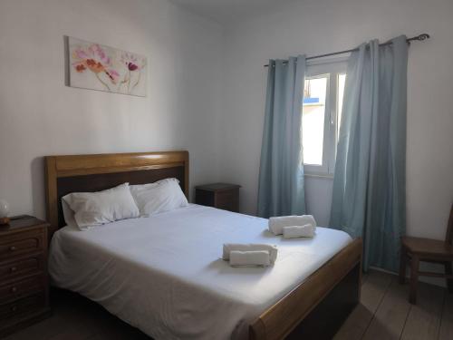 a bedroom with a bed with two towels on it at Apartamento Rosa in Porto Covo