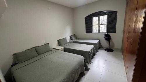 a room with three beds and a window at Casa Aparecida in Uberlândia