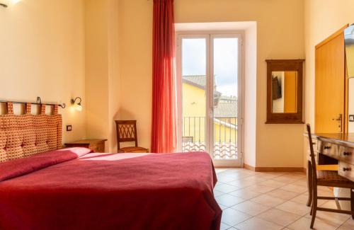a bedroom with a red bed and a balcony at Hotel Rossi in Manciano