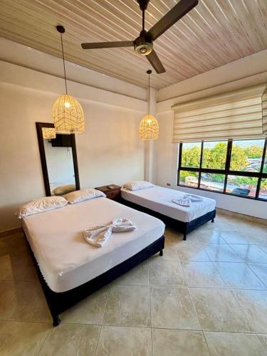 two beds in a room with two windows at Casa Raíces "Aire acondicionado, habitaciones familiares y económicas en La Dorada" in La Dorada
