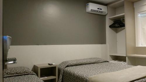 a small room with two beds and a window at Hotel Palmas Executivo in Balneário Camboriú