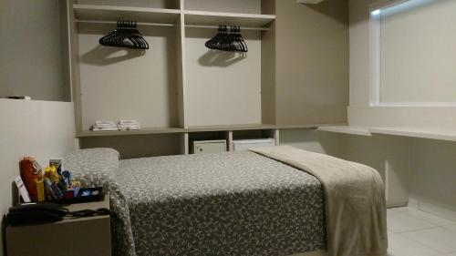 a bedroom with a bed and some shelves at Hotel Palmas Executivo in Balneário Camboriú