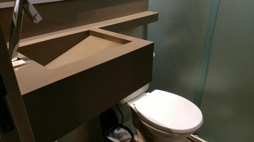 a bathroom with a white toilet and a sink at Hotel Palmas Executivo in Balneário Camboriú
