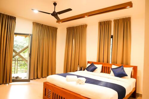 a bedroom with a large bed with blue and white pillows at ROCKs VILLA RESORT in Meppādi