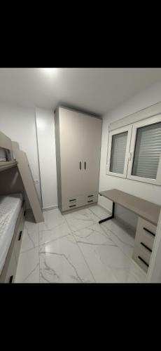 an empty room with a bed and two windows at Apartamento alhelí 2 in Barbate