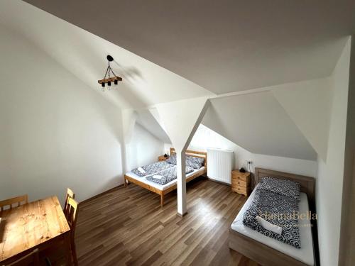 a attic room with two beds and a table at HannaBella Vendégház & Wellness in Miskolc