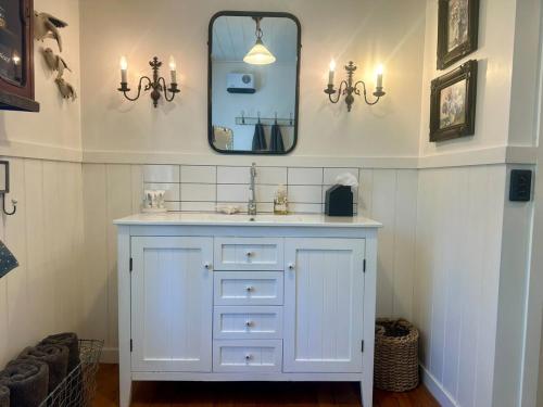 a bathroom with a white sink and a mirror at Gibbston Boathouse with Outdoor Bath in Gibbston
