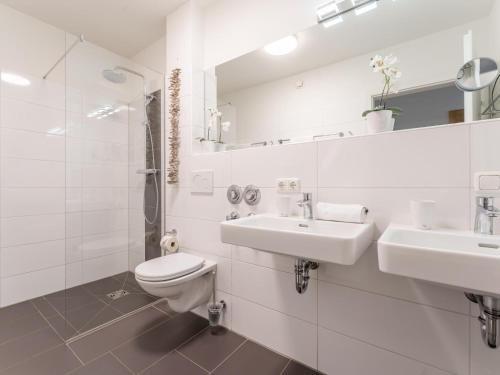 a white bathroom with two sinks and a toilet at Emma Top 2 in Dienten am Hochkönig