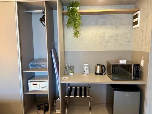 a kitchen with a counter with a microwave and a table at Hotel Bourbon - Quarto 1603 - Beira Mar de Fortaleza - Vista Mar in Fortaleza