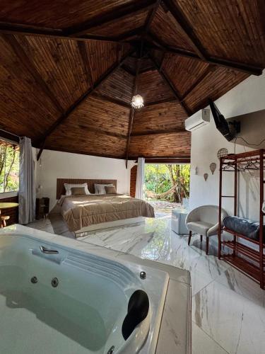 a bedroom with a bed and a large tub at Pousada Árvore Centenária in São Thomé das Letras