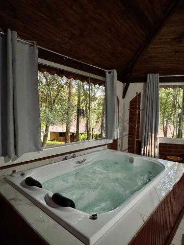 a large bath tub in a room with two windows at Pousada Árvore Centenária in São Thomé das Letras