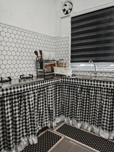 a kitchen with a black and white shower curtain at Homestay Seri Damai in Juasseh