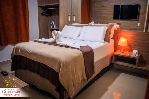 a bedroom with a large bed with a lamp on it at CONFORTO IMBATIVEL - 25 metros do MAR - 2 Quartos com AR CONDICIONADOS SPLIT, Air Fryer, WI-FI, Disney Plus, Star Plus, HBO Max, Cadeiras de Praia e Caixa Térmica - 8 pessoas com Muito Conforto - Melhor Localização! in Guarapari