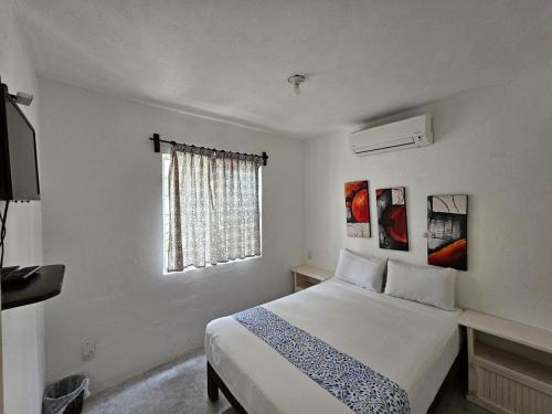 a white bedroom with a bed and a window at Alojamiento en las Huertas in Barrio Nuevo
