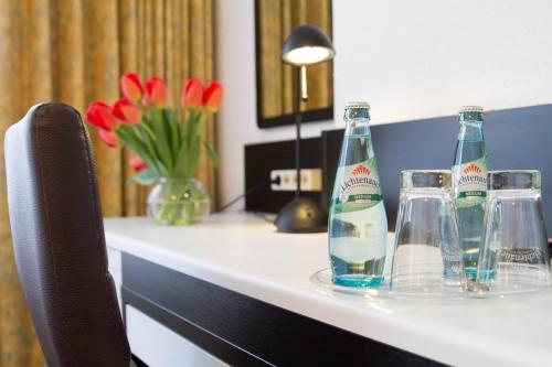 zwei Flaschen und Gläser auf einem Tisch mit Blumen in der Unterkunft Aparthotel VEGA in Berlin