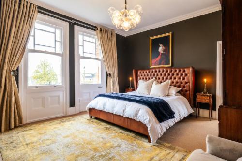 a bedroom with a large bed and a chandelier at Beautiful 5 Bedroom Home in Evesham in Evesham