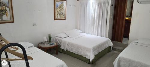 a small bedroom with two beds and a table at Hostal Casa de las Americas in Cartagena de Indias